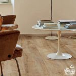 Brown Chair And A Table With Pile Of Books - Laminate Flooring Solutions - Woodland Lifestyle